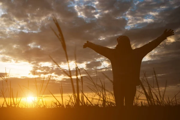 Silueta de mujer de pie en el campo durante la puesta del sol . — Foto de Stock