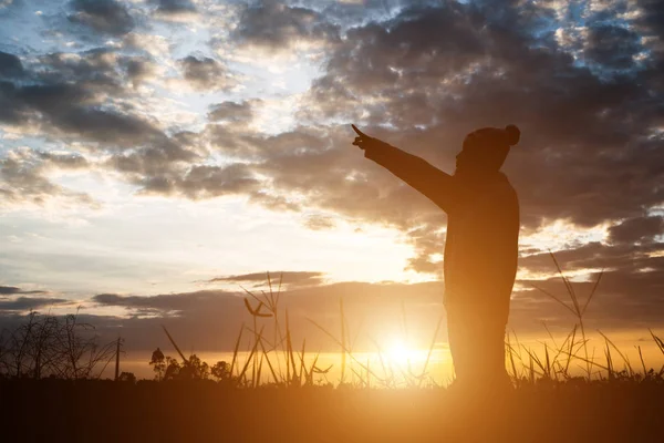 Silhueta de mulher em pé no campo durante o pôr do sol . — Fotografia de Stock