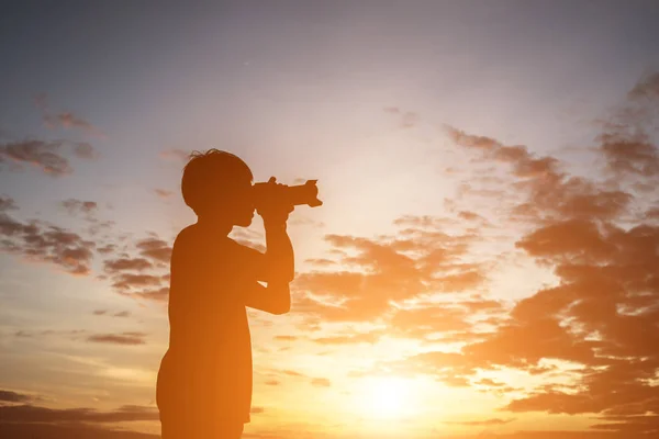 Silhouette eines jungen Mannes mit Kamera, die Arme ausstrecken, während — Stockfoto