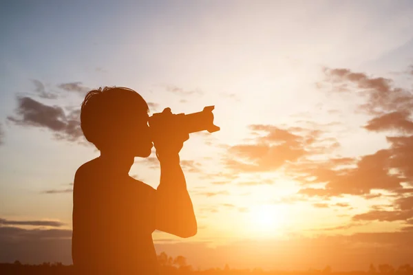 Silhouette eines jungen Mannes mit Kamera, die Arme ausstrecken, während — Stockfoto