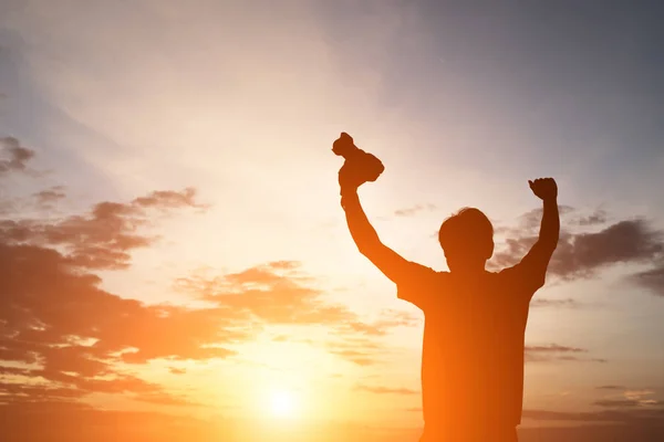 Silhouette of a young man  holding camera, extend the arms while — Stock Photo, Image