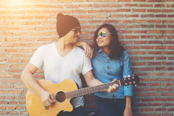 Hipster couple is hugging, looking away and smiling while standi