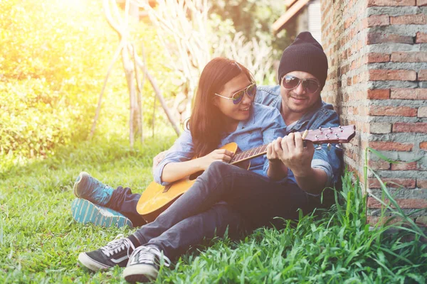 Hipster man leren gitaar spelen aan zijn vriendin terwijl sit — Stockfoto