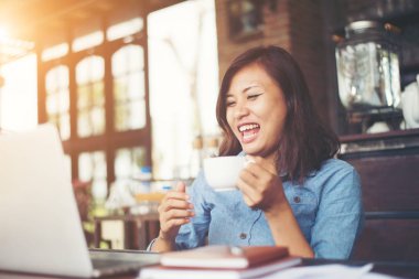 Kahve yudumlarken kafede dizüstü bilgisayar kullanan güzel hipster kadın