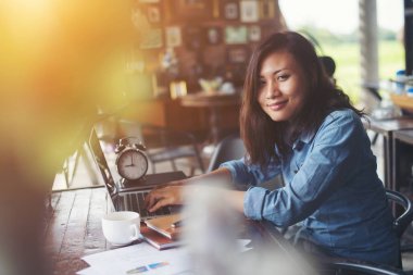 Kahve yudumlarken kafede dizüstü bilgisayar kullanan güzel hipster kadın