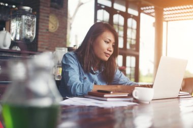Kahve yudumlarken kafede dizüstü bilgisayar kullanan güzel hipster kadın