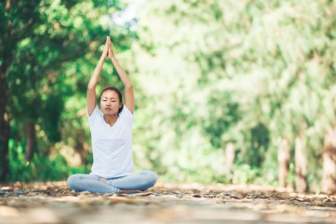Genç Asyalı kadın parkta sabah yoga yapıyor. Sağlıklı