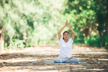 Genç Asyalı kadın parkta sabah yoga yapıyor. Sağlıklı