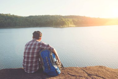 Erkek turistler su tek başına oturuyor. Doğa keyfini çıkarın.