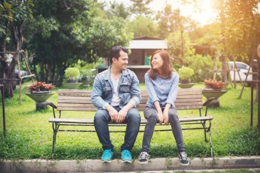 Birbirlerine benc üzerinde otururken seyir gülümseyen genç Çift