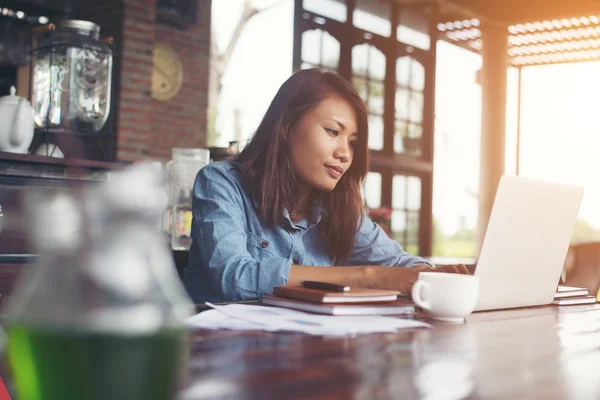 Hermosa mujer hipster utilizando el ordenador portátil en la cafetería mientras bebe coff — Foto de Stock