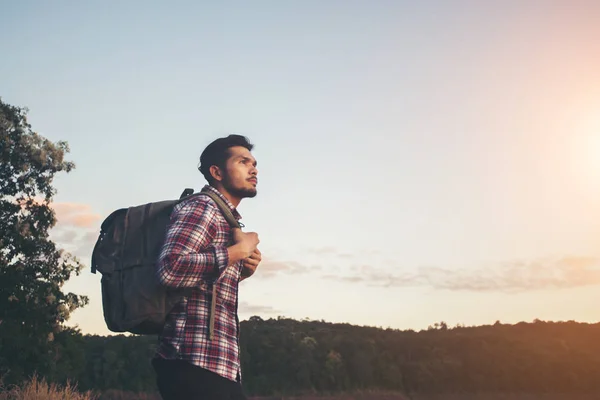 Hipster excursionista hombre de pie en la roca y disfrutar de la puesta del sol sobre — Foto de Stock