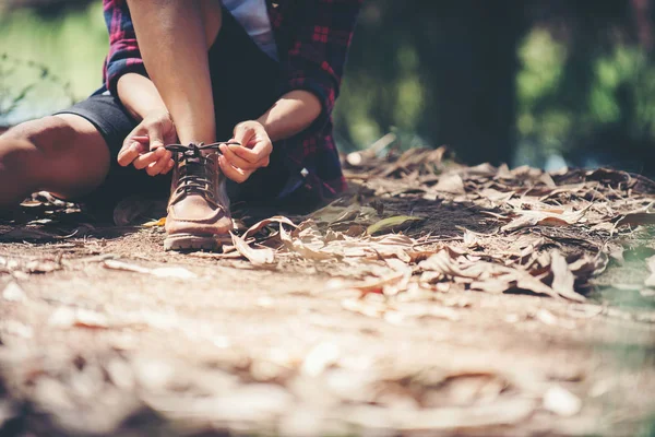 Jonge vrouw wandelaar stopt om haar schoen binden op een zomer-wandelweg — Stockfoto