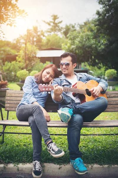 Akustik gitar s sırasında parkta oynarken aşık genç Çift — Stok fotoğraf