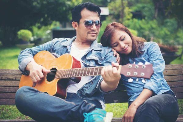 Akustik gitar s sırasında parkta oynarken aşık genç Çift — Stok fotoğraf