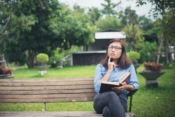 Hipster encantadora chica pensando algo mientras lee el libro rojo — Foto de Stock