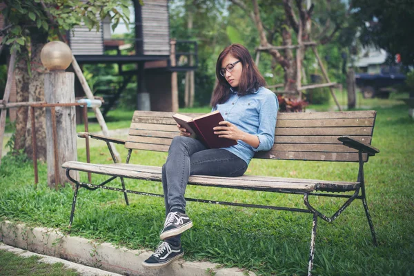Hipster charmante fille se détendre dans le parc tout en lisant le livre, Enjo — Photo