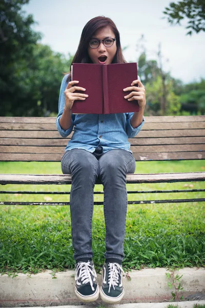 Encantadora chica hipster se sorprendió, leyendo una novela mientras sitti — Foto de Stock