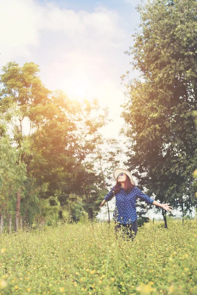 Jovem mulher atraente em pé em um campo de flores amarelas, ha — Fotografia de Stock
