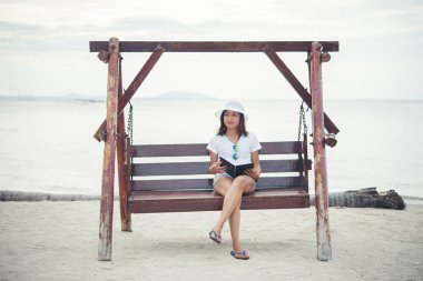 Güzel genç kadın bir salıncak onu not yazma arasında oturdu