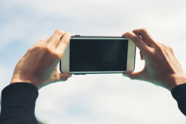 Erkek eller alarak fotoğraf ile smartphone, mavi gökyüzü görünümü ve