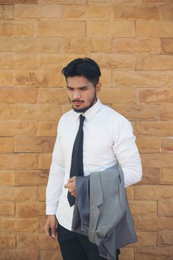Genç bir takım elbise tuğla duvara tutan işadamı.