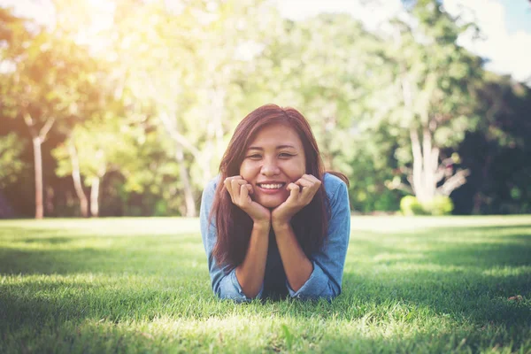 Charmante lachende jonge hipster vrouw liggend op groen gras. — Stockfoto