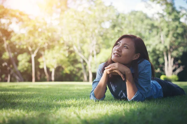 Charmante lachende jonge hipster vrouw liggend op groen gras. — Stockfoto