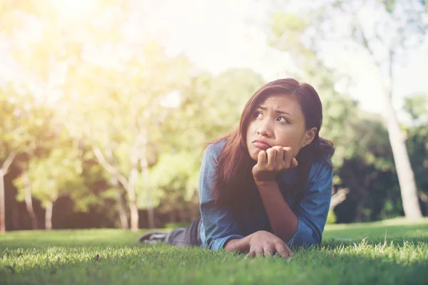 Charmante lachende jonge hipster vrouw liggend op groen gras. — Stockfoto