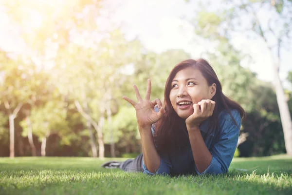 Charmante lachende jonge hipster vrouw liggend op groen gras. — Stockfoto