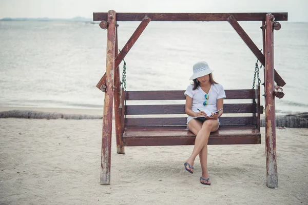 Gyönyörű, fiatal nő ült a swing között írásban a lány Megjegyzés — Stock Fotó