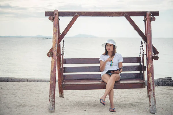 Güzel genç kadın bir salıncak onu not yazma arasında oturdu