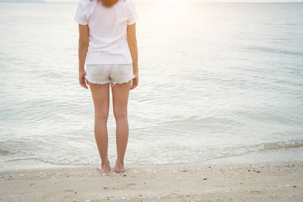 Ung kvinna stående på stranden med barfota. — Stockfoto