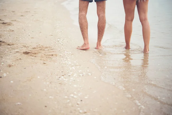 Achterzijde van jong koppel wandelen op het strand met blote voeten. — Stockfoto