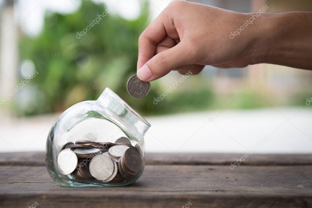 Man hands saving money into bottle for cash in future investment