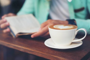 Adam okuma ve sabah kafede kahve içer.