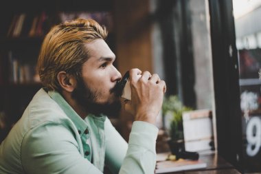 Hipster adam oturan tek kullanımlık kağıt bardak kahve içme