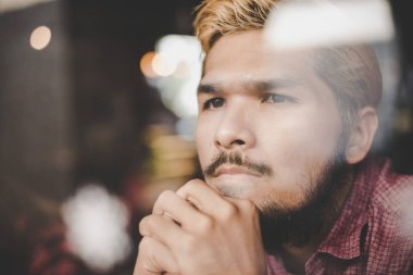 Kahve Dükkanı düşüncesinde ve lo oturan dalgın genç hipster adam