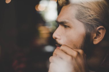 Kahve Dükkanı düşüncesinde ve lo oturan dalgın genç hipster adam