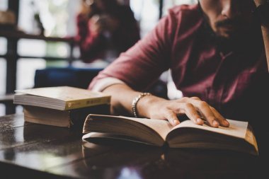 Hippi sakallı adam kafede kitap okuyor..