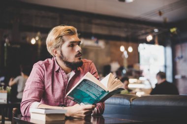 Hippi sakallı adam kafede kitap okuyor..