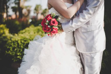 Gelin düğün kırmızı gül buketi elinde tutan, damat hugs 