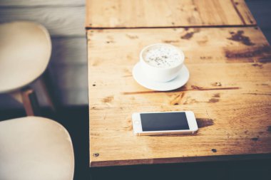 Bir fincan kahve ve Cafe ahşap masa üstünde smartphone. Kahve b