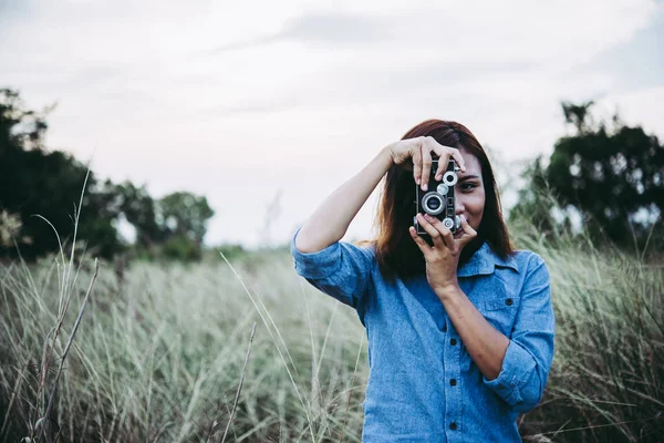 Mujer hipster joven feliz con cámara vintage en el campo. Disfrute de wi — Foto de Stock