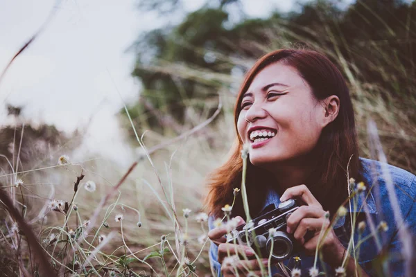 Happy young hipster woman with vintage camera in field. Enjoy wi