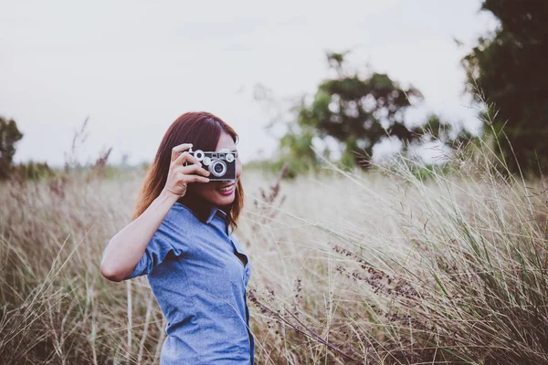 Happy young hipster woman with vintage camera in field. Enjoy wi