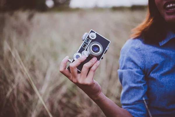Mujer hipster joven feliz con cámara vintage en el campo. Disfrute de wi —  Fotos de Stock