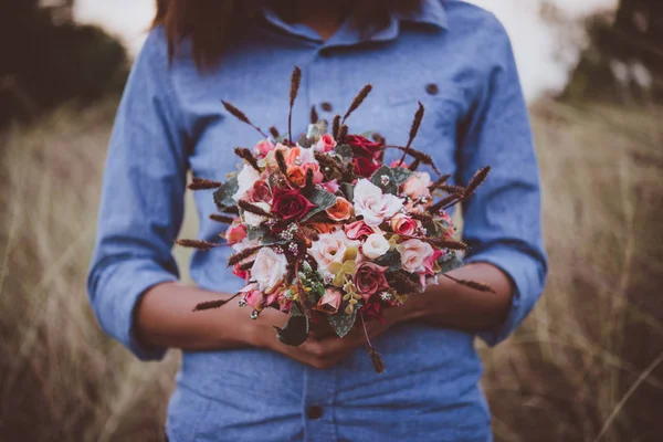 Young hipster woman in field holding a bouquet of red rose, summ — Stock Photo, Image