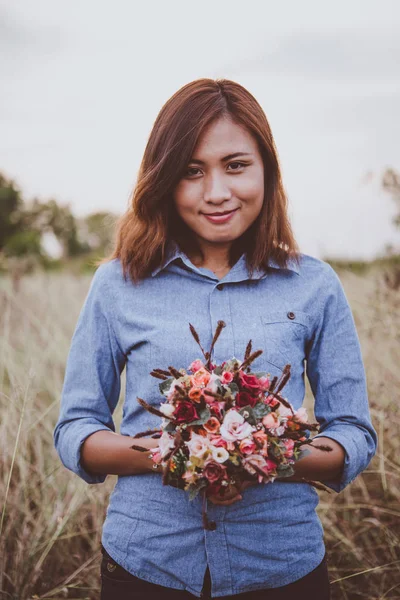 Young hipster woman in field holding a bouquet of red rose, summ