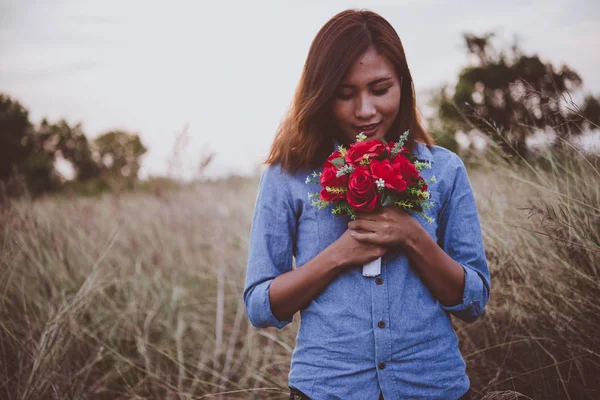 Jeune femme hipster dans le champ tenant un bouquet de rose rouge, summ — Photo